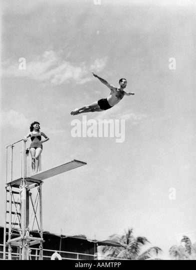 1930s-1940s-shapely-woman-watching-man-swan-dive-off-high-diving-board-aamtpp.jpg